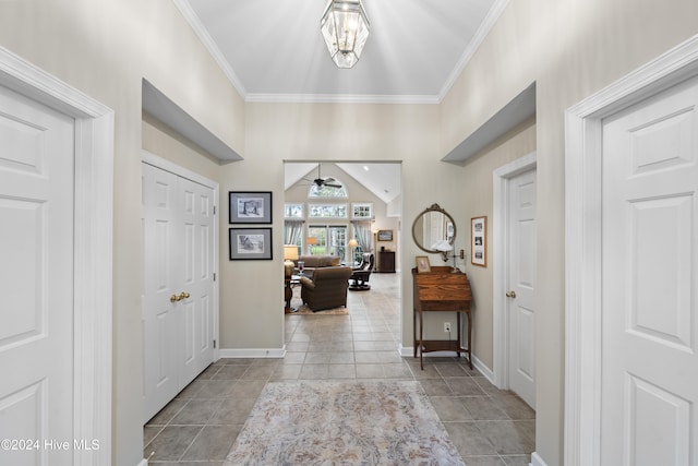 foyer entrance featuring ceiling fan, crown molding, light tile patterned floors, and vaulted ceiling