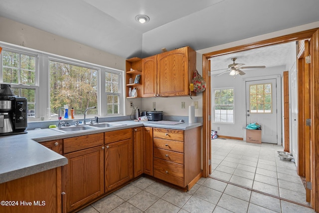 kitchen with a healthy amount of sunlight, light tile patterned flooring, lofted ceiling, and sink