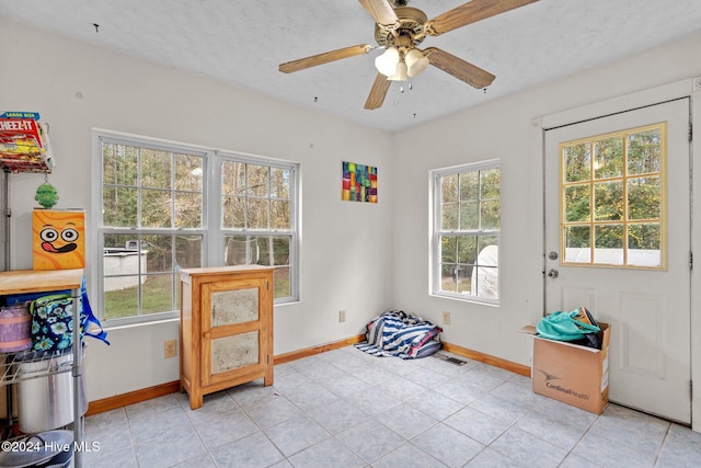 interior space with ceiling fan, light tile patterned flooring, and a textured ceiling