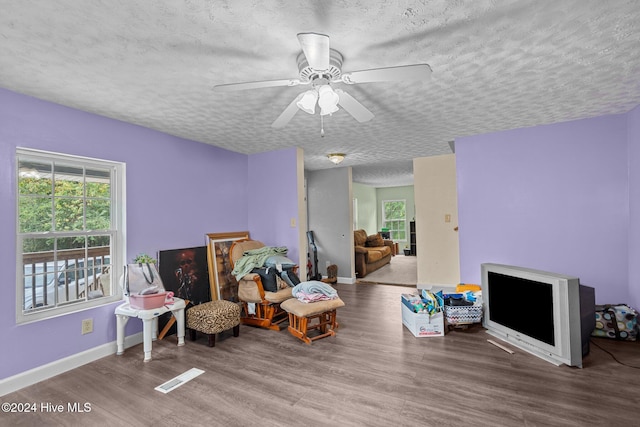 sitting room featuring hardwood / wood-style floors, ceiling fan, and a textured ceiling