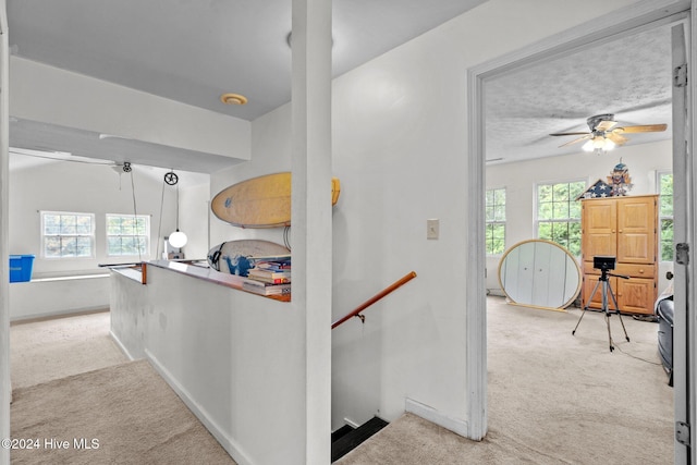 hallway featuring light colored carpet and a textured ceiling