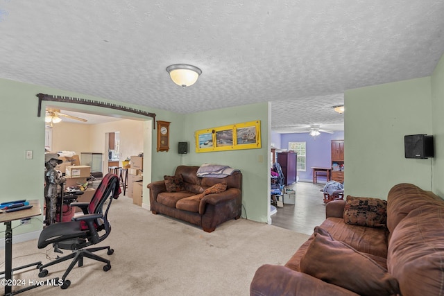 carpeted living room with a textured ceiling and ceiling fan