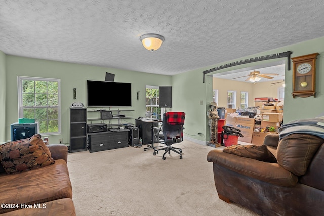 carpeted office space featuring ceiling fan and a textured ceiling