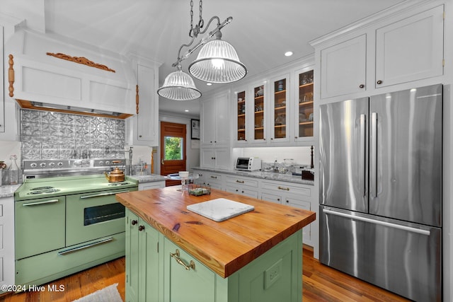 kitchen with stainless steel refrigerator, white cabinetry, electric range oven, butcher block countertops, and a kitchen island