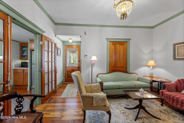 living room with a chandelier, hardwood / wood-style flooring, and crown molding