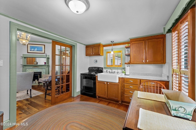505 Broad St, Oriental, NC 28571 - kitchen with black range with electric stovetop, a sink, light countertops, wood finished floors, and brown cabinetry