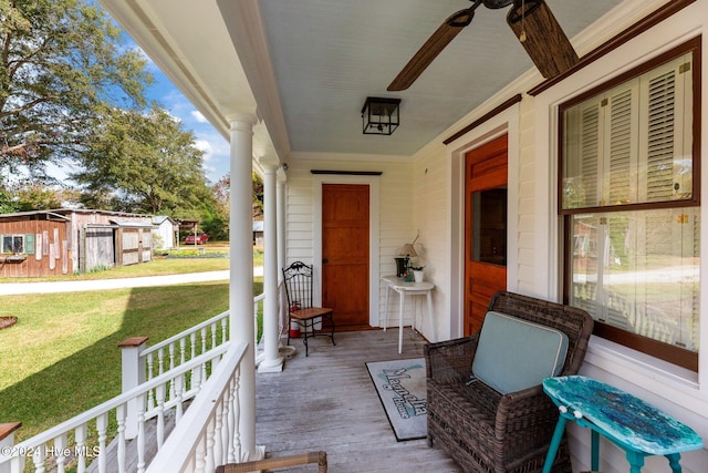 wooden deck featuring a lawn, ceiling fan, and a porch