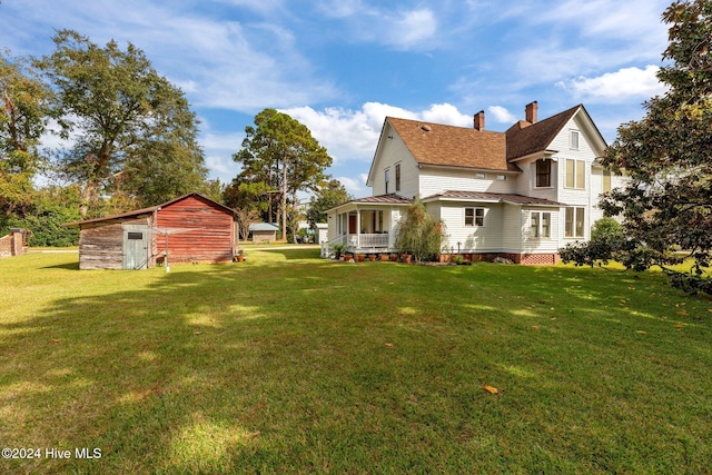 rear view of house featuring covered porch, a storage shed, and a lawn