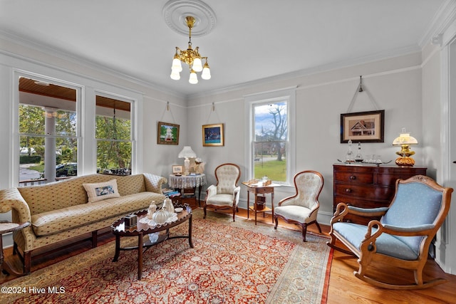 living room with an inviting chandelier, light hardwood / wood-style floors, and ornamental molding