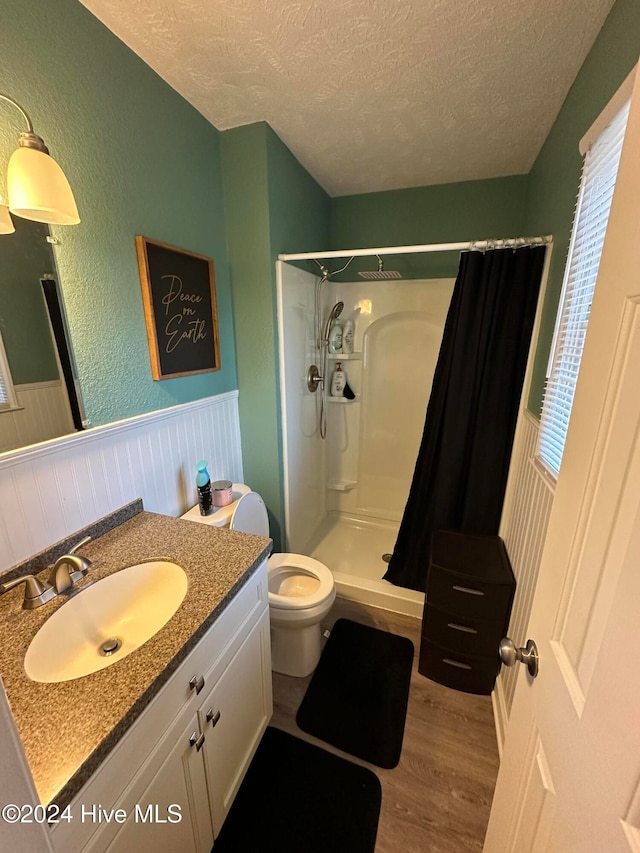 bathroom featuring toilet, wood-type flooring, a textured ceiling, and a shower with shower curtain