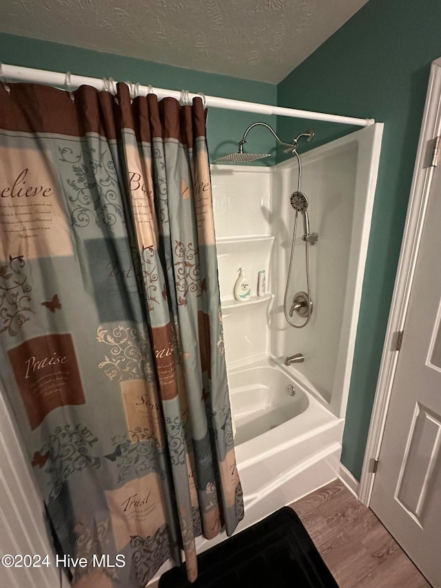 bathroom featuring shower / bath combo with shower curtain, wood-type flooring, and a textured ceiling