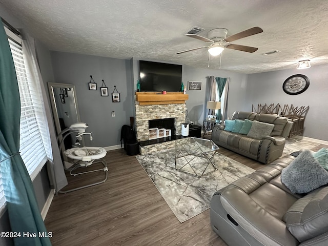 living room with a fireplace, ceiling fan, wood-type flooring, and a textured ceiling