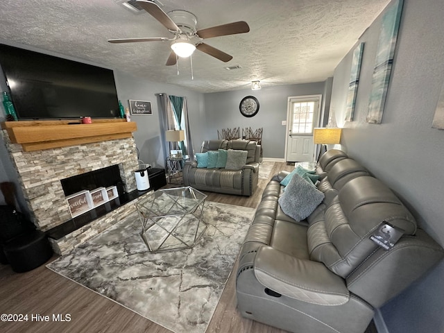 living room with a fireplace, wood-type flooring, a textured ceiling, and ceiling fan