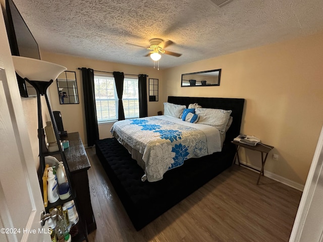 bedroom with a textured ceiling, ceiling fan, and dark wood-type flooring