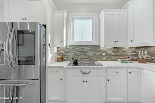 kitchen featuring tasteful backsplash, stainless steel fridge, black electric stovetop, and white cabinets