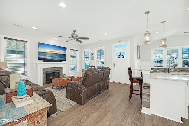 living room featuring ceiling fan, light hardwood / wood-style floors, lofted ceiling, and sink