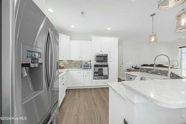 kitchen with light hardwood / wood-style floors, decorative light fixtures, decorative backsplash, white cabinets, and appliances with stainless steel finishes