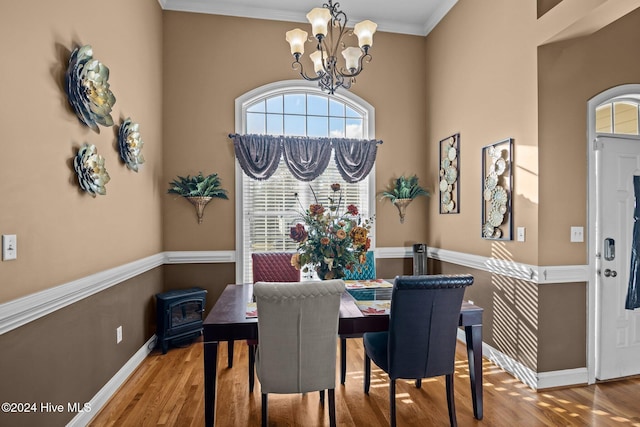 dining area featuring wood-type flooring, an inviting chandelier, and crown molding