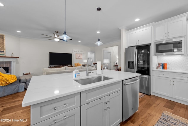 kitchen featuring sink, light hardwood / wood-style floors, decorative backsplash, white cabinets, and appliances with stainless steel finishes