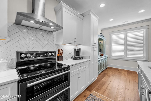 kitchen featuring white cabinets, light hardwood / wood-style flooring, wall chimney exhaust hood, and stainless steel range with electric cooktop