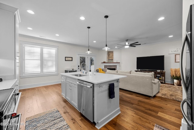 kitchen with sink, stainless steel appliances, wood-type flooring, a kitchen island with sink, and white cabinets