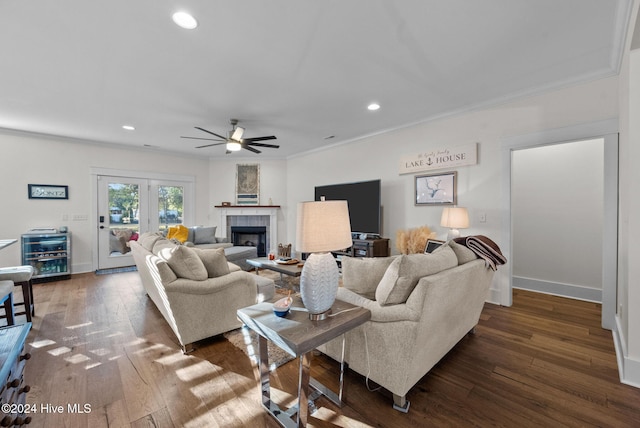 living room with dark hardwood / wood-style floors, ceiling fan, crown molding, and a tiled fireplace