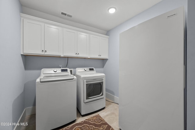 laundry room with baseboards, visible vents, cabinet space, and washing machine and clothes dryer