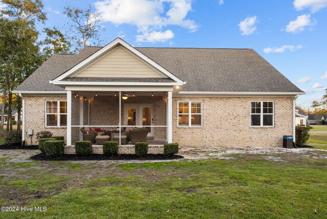 rear view of house featuring ceiling fan, a patio area, an outdoor living space, and a yard