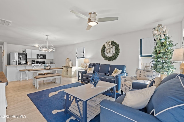 living room with light hardwood / wood-style flooring and ceiling fan with notable chandelier