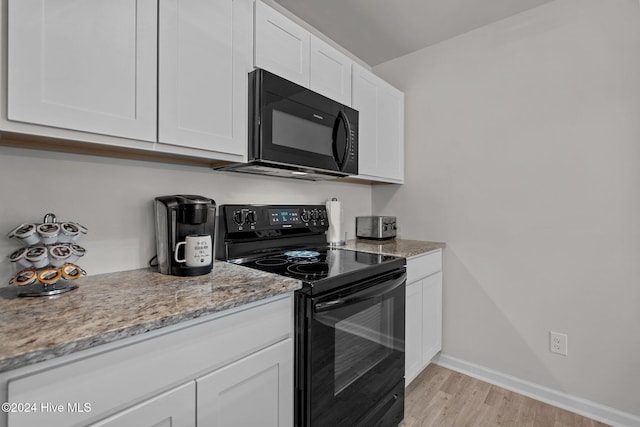 kitchen featuring black appliances, white cabinets, light wood-type flooring, and light stone counters