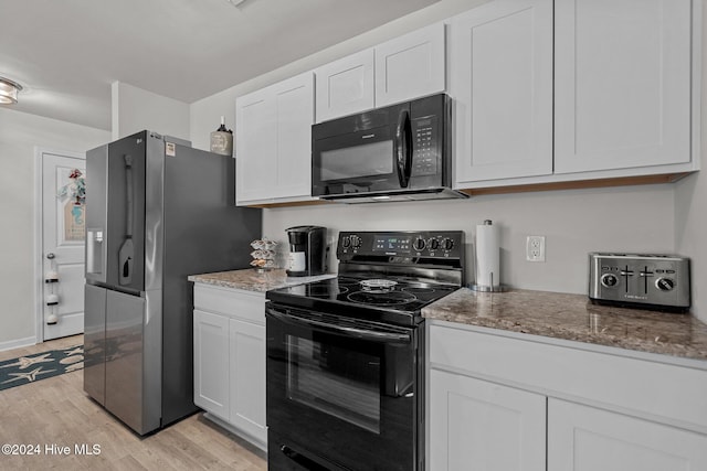 kitchen with light stone countertops, white cabinetry, black appliances, and light hardwood / wood-style floors