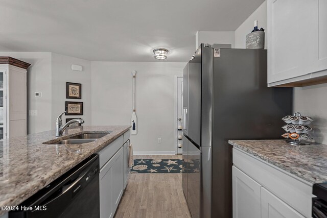 kitchen featuring black dishwasher, sink, white cabinets, and light hardwood / wood-style flooring