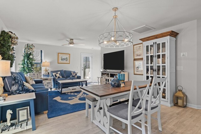 living room featuring ceiling fan with notable chandelier and light hardwood / wood-style flooring