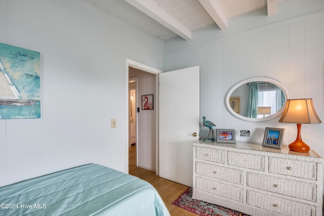 bedroom featuring beam ceiling and light wood-type flooring