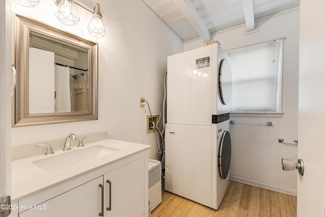 laundry area featuring stacked washer and dryer, light hardwood / wood-style flooring, wood ceiling, and sink