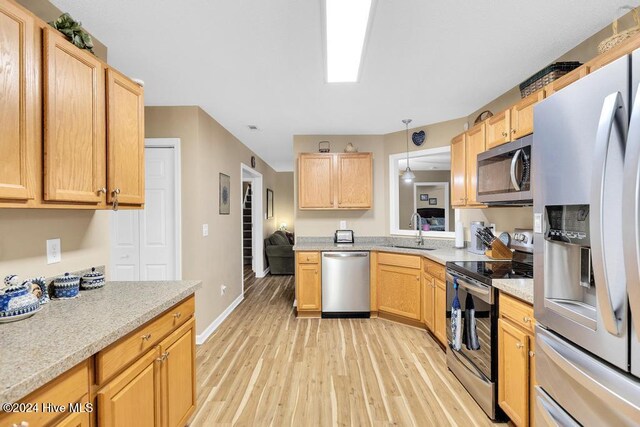 kitchen with light brown cabinetry, sink, light hardwood / wood-style flooring, pendant lighting, and stainless steel appliances