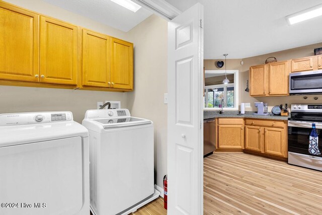 washroom with sink, separate washer and dryer, and light wood-type flooring