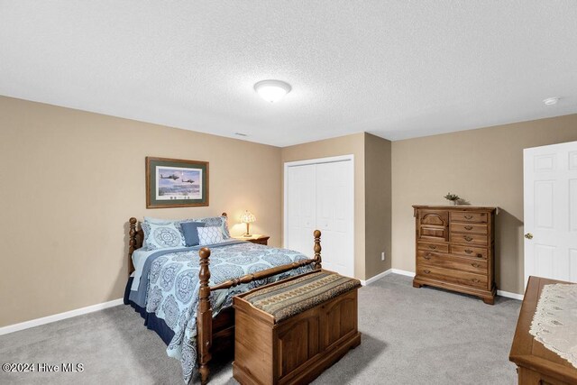 bedroom featuring a textured ceiling, light colored carpet, and a closet