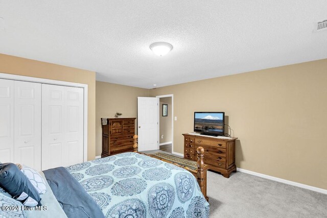 bedroom with a closet, light colored carpet, and a textured ceiling