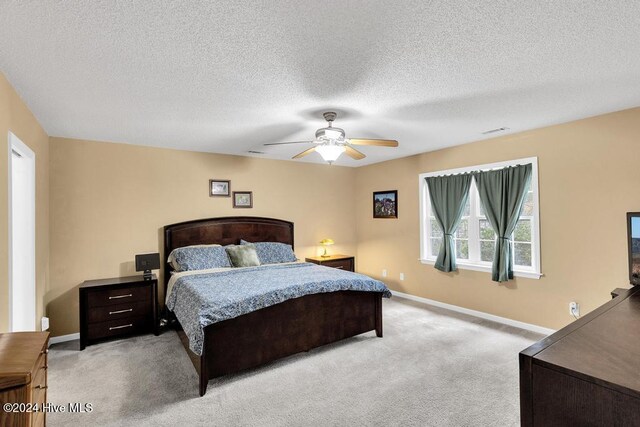 bedroom featuring light carpet, a textured ceiling, and ceiling fan