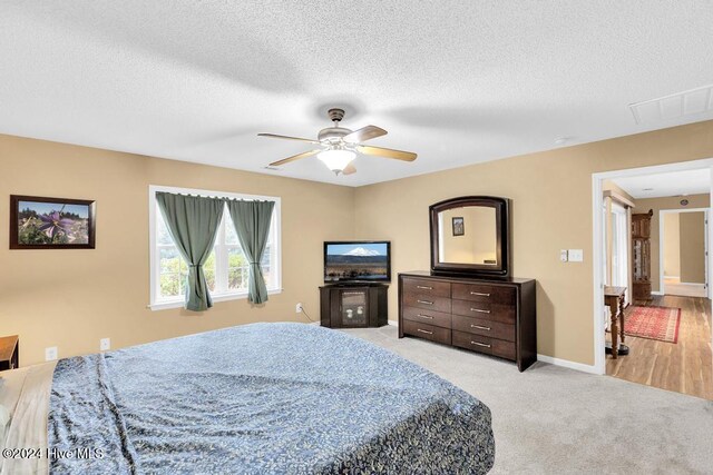 bedroom with light carpet, a textured ceiling, and ceiling fan