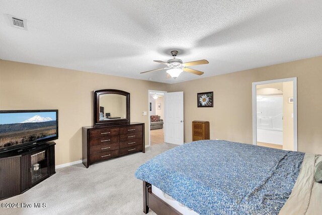 carpeted bedroom featuring ceiling fan, a textured ceiling, and ensuite bath