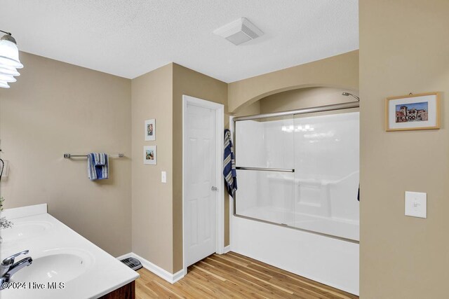 bathroom featuring vanity, combined bath / shower with glass door, hardwood / wood-style floors, and a textured ceiling