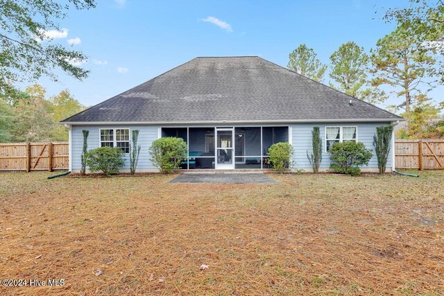 rear view of property with a lawn, a sunroom, and a patio area