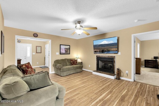 living room featuring light hardwood / wood-style floors, a textured ceiling, and ceiling fan