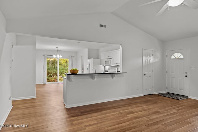 entrance foyer with ceiling fan with notable chandelier, high vaulted ceiling, and light hardwood / wood-style flooring