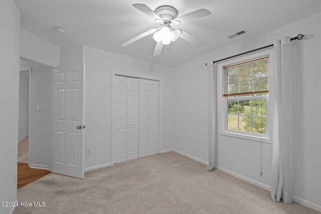 unfurnished bedroom with light colored carpet, visible vents, baseboards, and ensuite bathroom