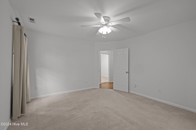 carpeted empty room with ceiling fan, visible vents, and baseboards