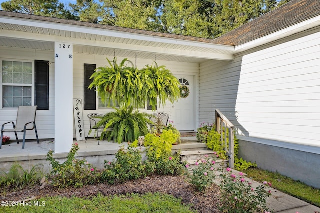 doorway to property with a porch and roof with shingles