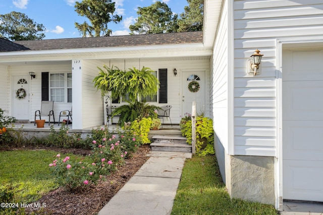 property entrance featuring a garage, a porch, and roof with shingles